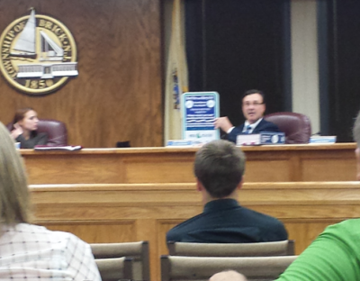 Councilman Jim Fozman holds up a sign that will be posted near fishing line recycling receptacles.