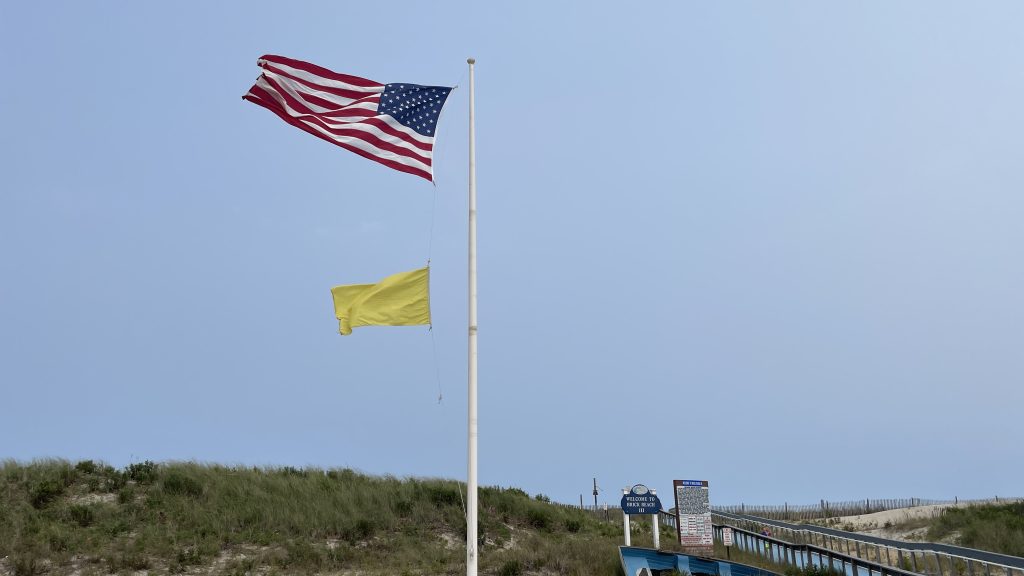 A single-yellow flag flies at Brick Beach III, Aug. 2023. (Photo: Shorebeat)